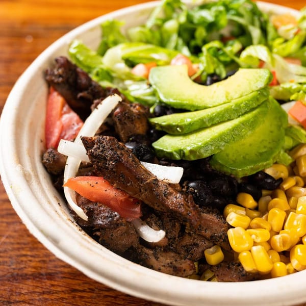 Latin Chicks' bowl with seasoned meat, corn, black beans, avocado, tomatoes, onions, and lettuce.