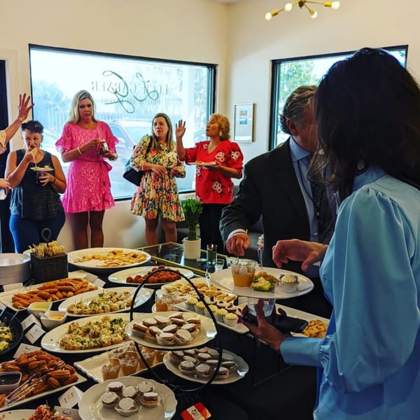 Guests gather around a table laden with various Latin-American appetizers and desserts at Latin Chicks.